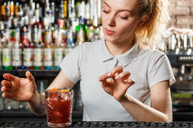 Camarero mujer haciendo un cóctel de alcohol en el bar.