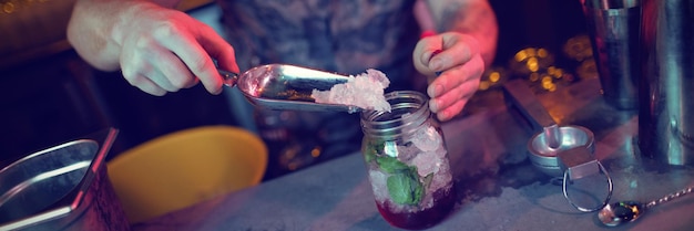 Camarero poniendo hielo en la jarra mientras prepara el cóctel