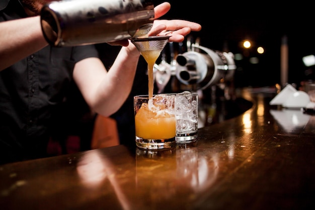 Un camarero profesional vierte hielo en un vaso para beber Tiempo para una fiesta en una discoteca