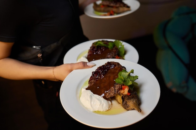 Camarero que lleva dos platos con plato de carne en algún evento festivo, fiesta de bodas o evento atendido