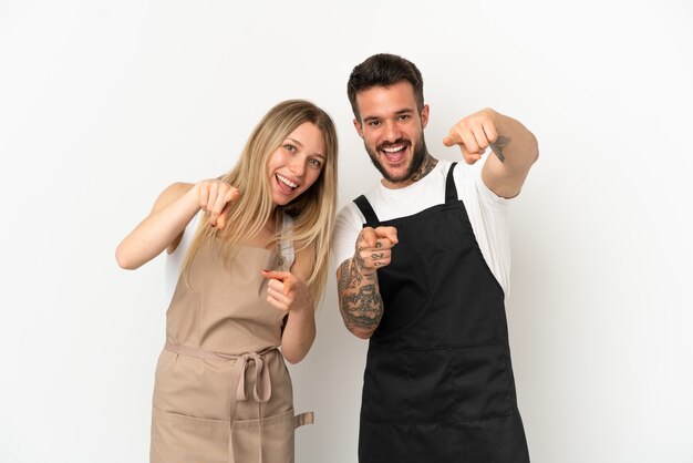 El camarero del restaurante sobre fondo blanco aislado le señala con el dedo mientras sonríe