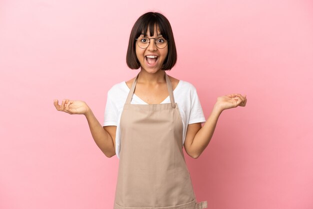 Camarero de restaurante sobre fondo rosa aislado con expresión facial de sorpresa