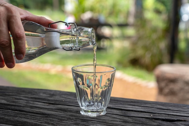 Un camarero en un restaurante vierte agua fresca de una botella en un vaso de cerca