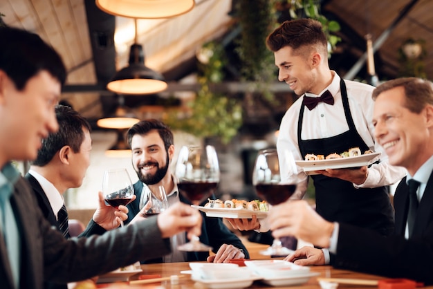 Camarero sirve bebidas y comida para empresas chinas.