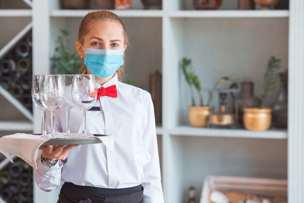 El camarero sirve una mesa en un café con una máscara protectora.