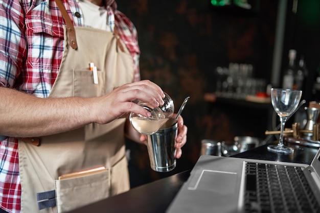 Foto camarero sirviendo un cóctel de una coctelera en un vaso