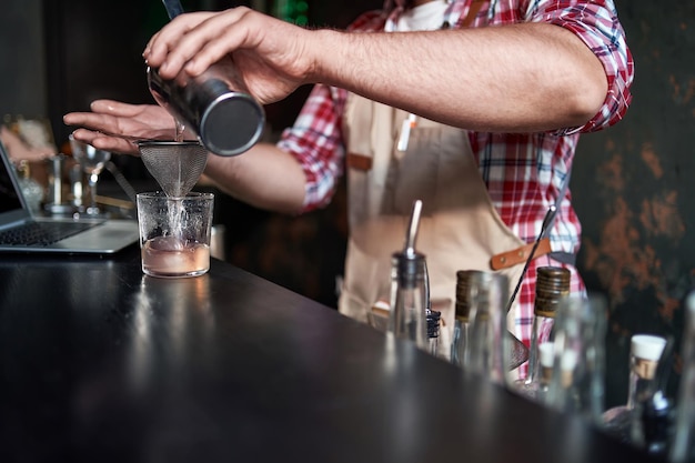 Foto camarero sirviendo un cóctel de una coctelera en un vaso