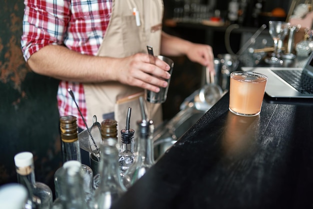 Foto camarero sirviendo un cóctel de una coctelera en un vaso