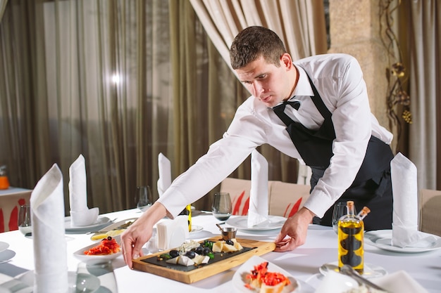 Camarero sirviendo mesa en el restaurante preparándose para recibir a los invitados.