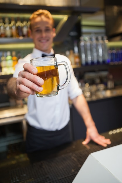 Foto camarero sonriente ofreciendo cerveza a la cámara