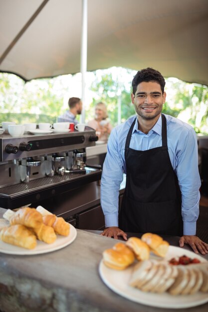 Camarero sonriente de pie cerca del mostrador en el restaurante