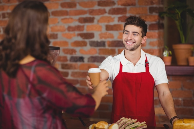 Camarero sonriente sirviendo un café a un cliente