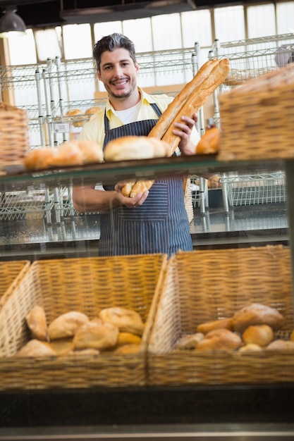 Camarero sonriente sosteniendo dos baguettes