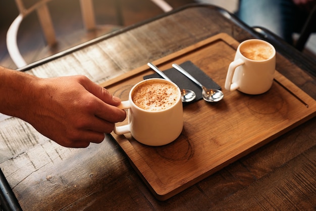 Camarero sosteniendo una bandeja con cafés en la barra.