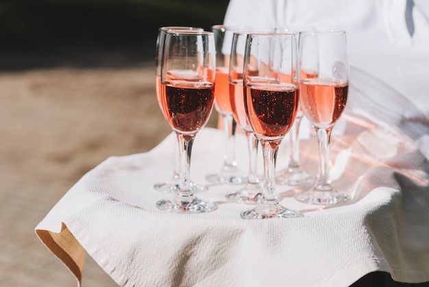 Camarero sosteniendo una bandeja de copas de vino espumoso rosado