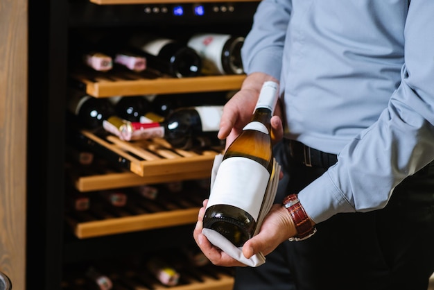 Un camarero sosteniendo una botella de vino en el fondo de la bodega