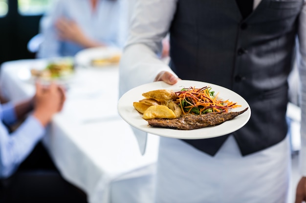 Foto camarero sosteniendo un plato de comida