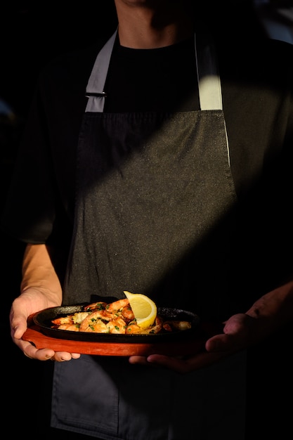 El camarero sostiene un plato de camarones