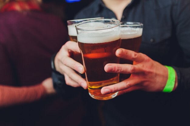 Camarero sostiene vasos de cerveza en las manos en un bar o pub