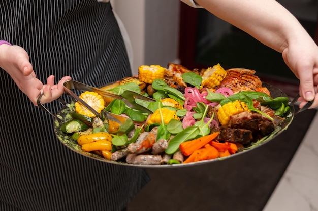 El camarero trajo un plato de carne y verduras fritas en un wok.