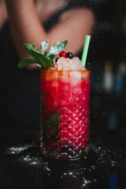 Camarero vertiendo azúcar glas sobre mojito de frutas en un pub