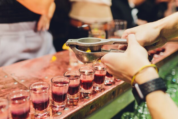 Camarero vertiendo bebidas alcohólicas fuertes en vasos pequeños en la barra, disparos.