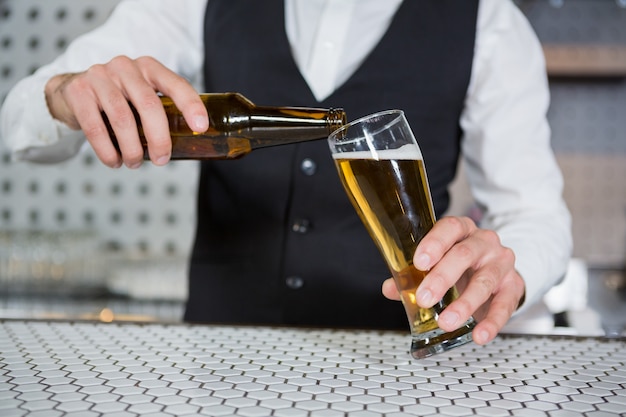 Camarero vertiendo cerveza en vaso