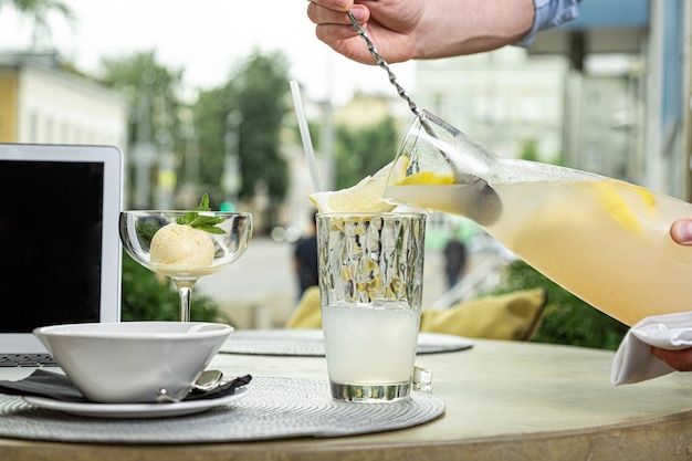 El camarero vierte agua con limón y menta en vasos sobre una mesa para servir