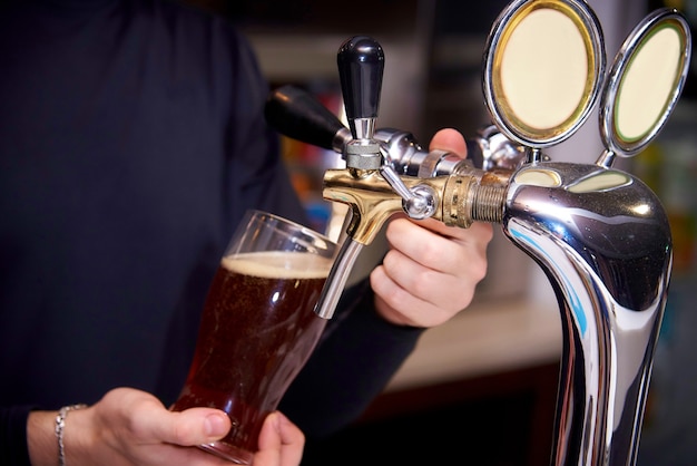 El camarero vierte una cerveza en un vaso.