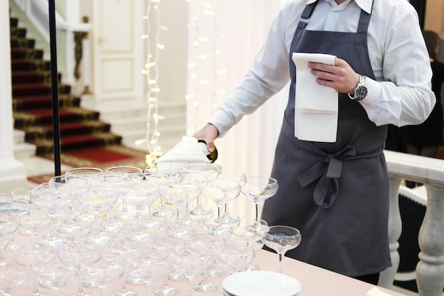 El camarero vierte champán en copas en la mesa del bufé