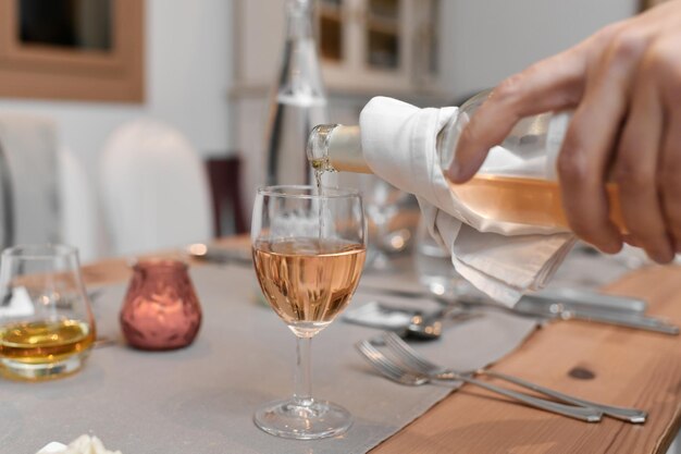 Un camarero vierte el vino francés rosado en el vaso.