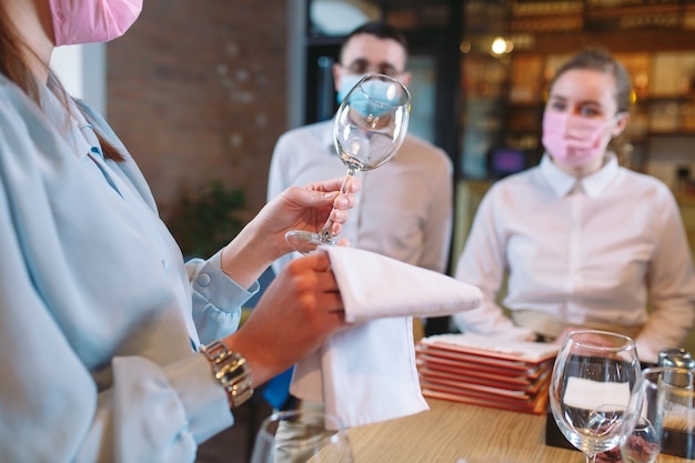 Los camareros del restaurante con una máscara médica aprenden a distinguir entre los vasos