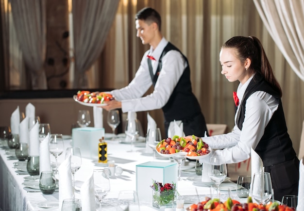 Camareros sirviendo mesa en el restaurante preparándose para recibir invitados.