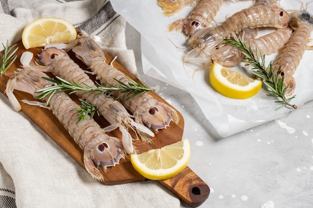 Foto camarões de grande louva-a-deus frescos de frutos do mar crus com limão em um fundo cinza de concreto. ingredientes em uma loja ou restaurante de frutos do mar, plano de fundo para um menu de peixes