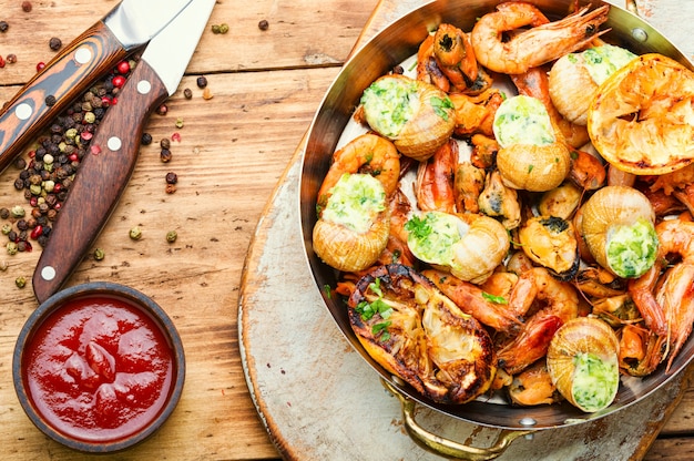 Camarões grelhados, mexilhões e caracóis recheados. Deliciosos frutos do mar na mesa de madeira