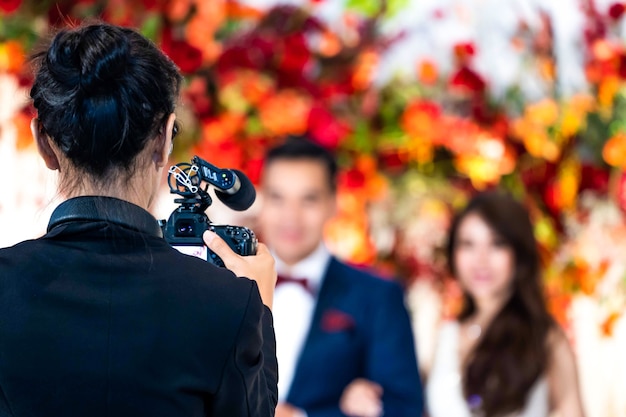 La camarógrafa en la parte trasera está grabando y grabando videos en un evento de boda.