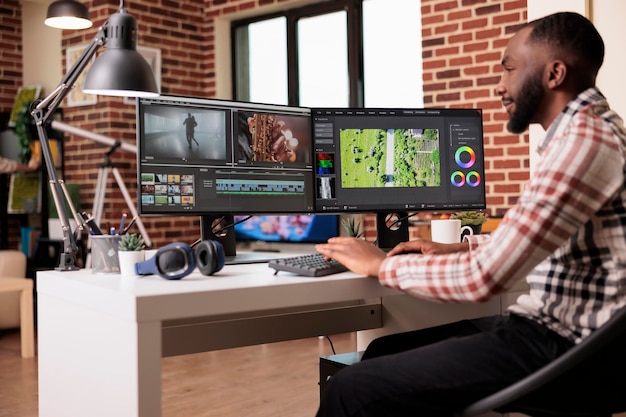 Camarógrafo afroamericano que mejora el metraje de video usando software de edición para hacer contenido de postproducción. Uso de gradación de color y efectos visuales o de audio para editar proyectos de montaje de películas en casa.