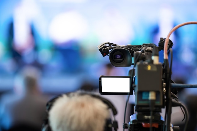 El camarógrafo asiático en la parte trasera está disparando y grabando video en el evento Speech en el escenario