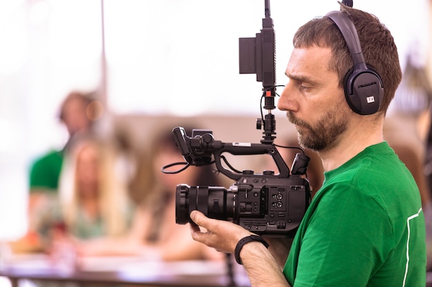 Camarógrafo filmando una película o un programa de televisión en un estudio con una cámara profesional, entre bastidores