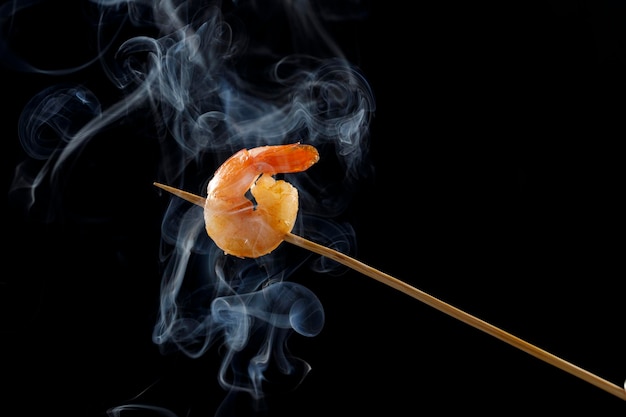 un camarón en una brocheta con un hermoso humo