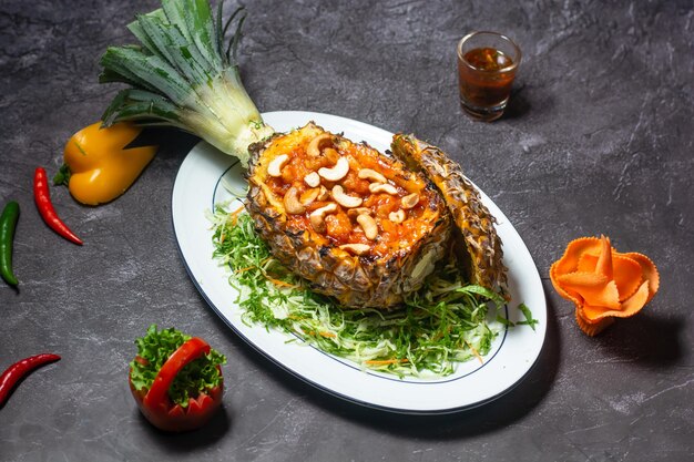 Camarones al horno sobre piña con anacardos y salsa servidos en un plato aislado en la vista superior de fondo gris de la comida india y bangladesh