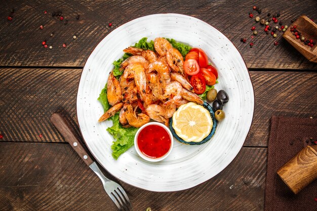 Camarones asados con salsa roja y limón en la mesa decorada de madera