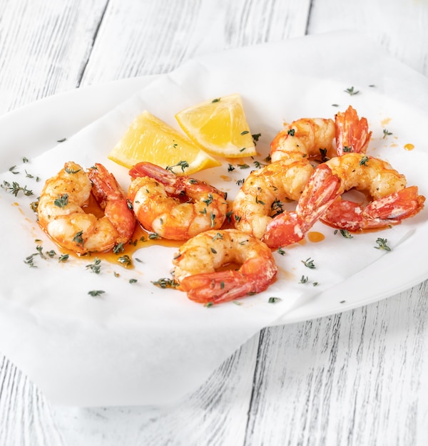 Camarones cocidos con rodajas de tomillo y limón en un plato para servir