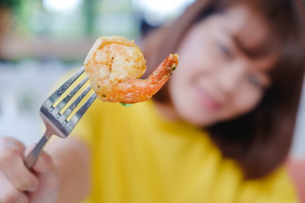 Camarones cocidos en tenedor sujetar por mujer con fondo borroso