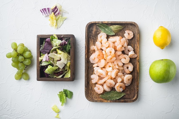 Camarones crudos frescos enteros pelados hervidos para ensalada de gambas Waldorf, con salsa de manzana y uva, sobre la mesa de piedra blanca, vista superior laicos plana