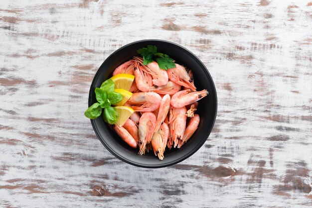 Camarones crudos con limón en el plato sobre un fondo blanco Vista superior de madera Espacio de copia libre