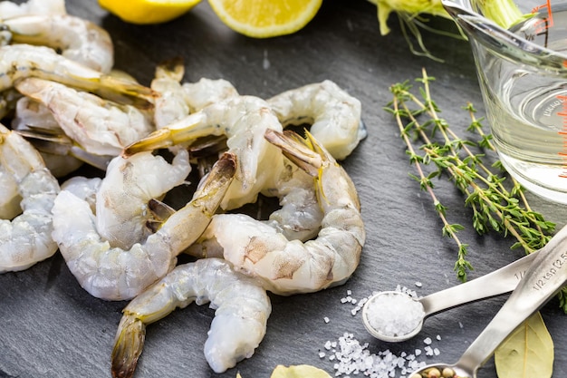 Camarones crudos pelados con colas con limón sobre tablero de sutura.