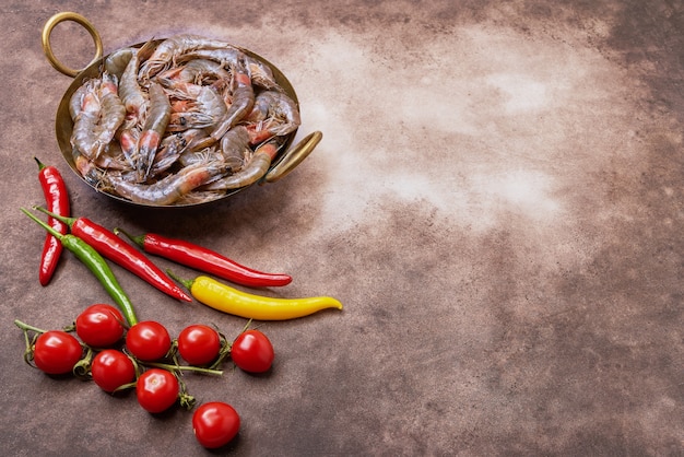 Camarones frescos crudos en un plato del vintage sobre fondo marrón. Copia espacio