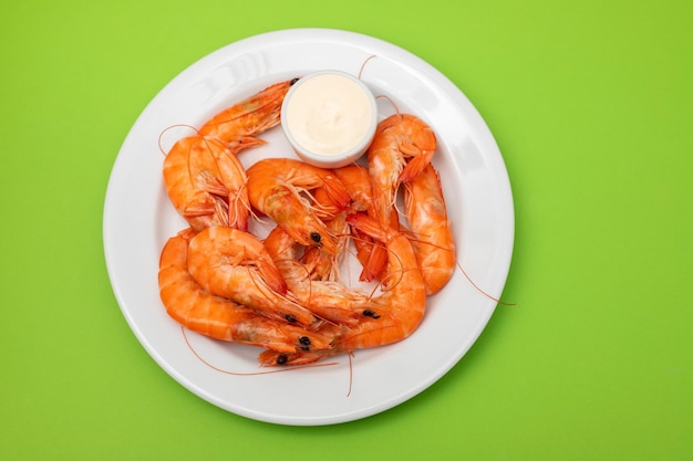 Camarones frescos hervidos con salsa en un tazón pequeño en un plato blanco sobre verde