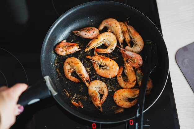 Camarones fritos en aceite en sartén con especias. De cerca